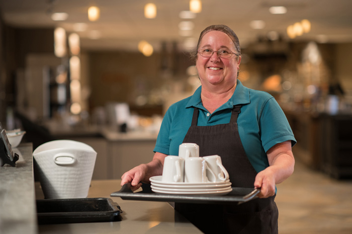 Female worker holding a tray of dishes