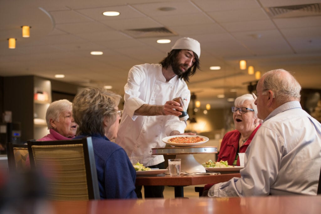 Chef serving pizza to four residents